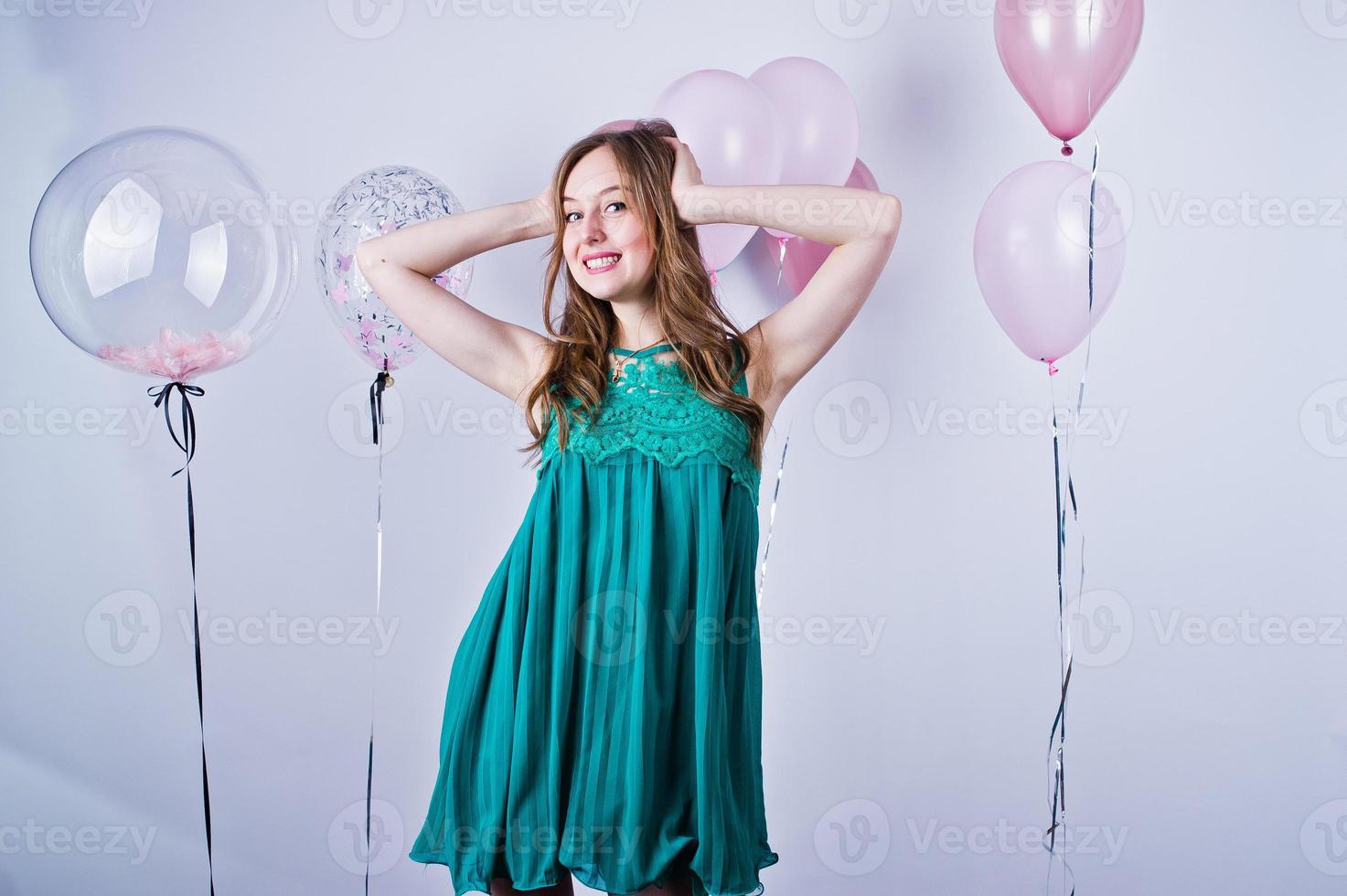 fille heureuse en robe turquoise verte avec des ballons colorés isolés sur blanc. célébrer le thème de l'anniversaire. photo