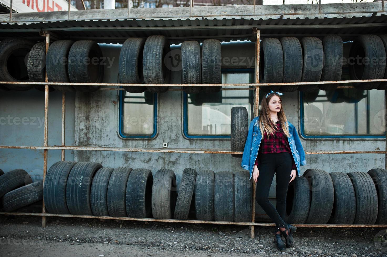 jeune fille hipster en veste jeans et foulard à la zone de montage des pneus. photo