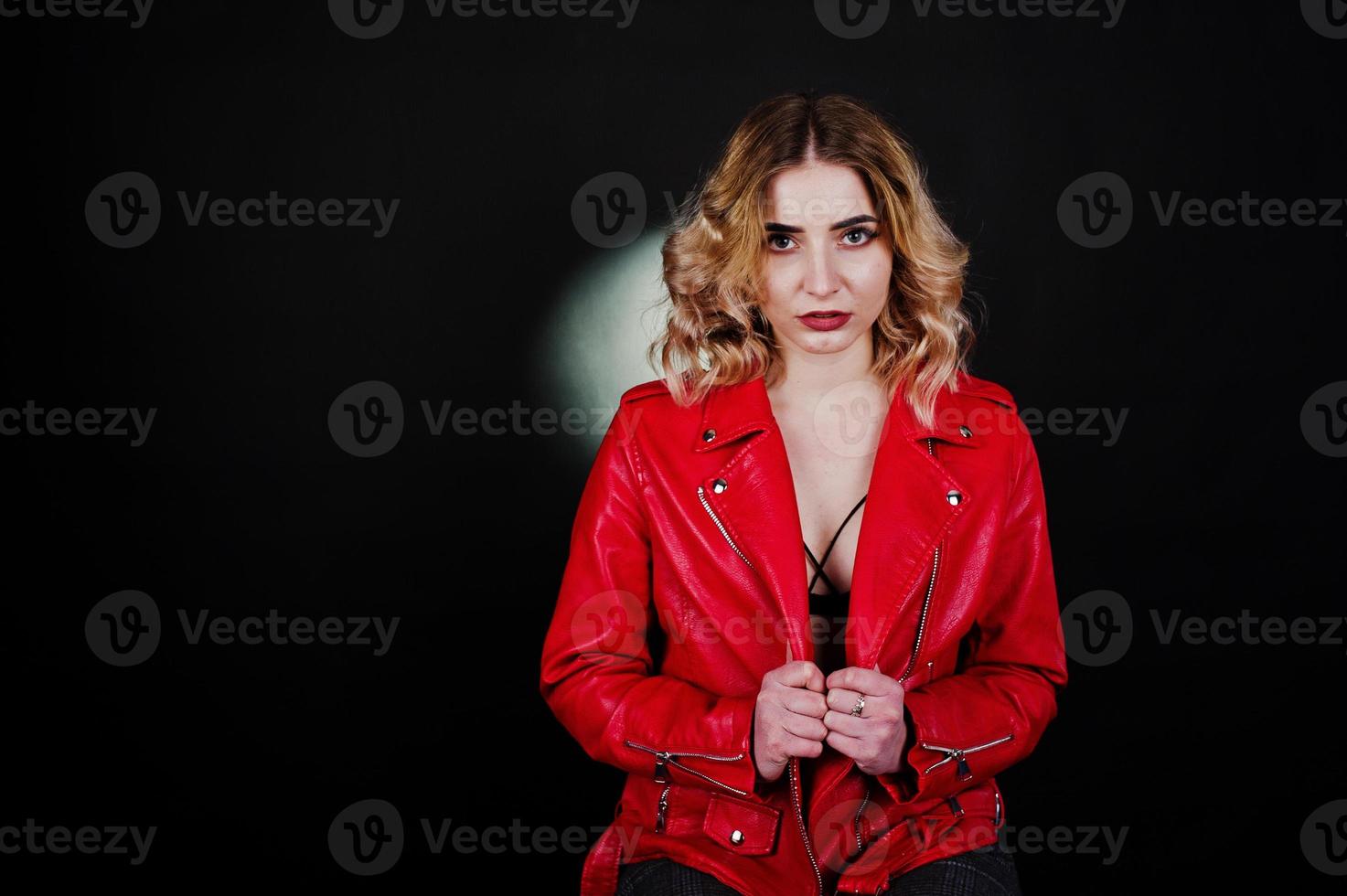 portrait en studio de jeune fille blonde en veste de cuir rouge sur fond noir. photo