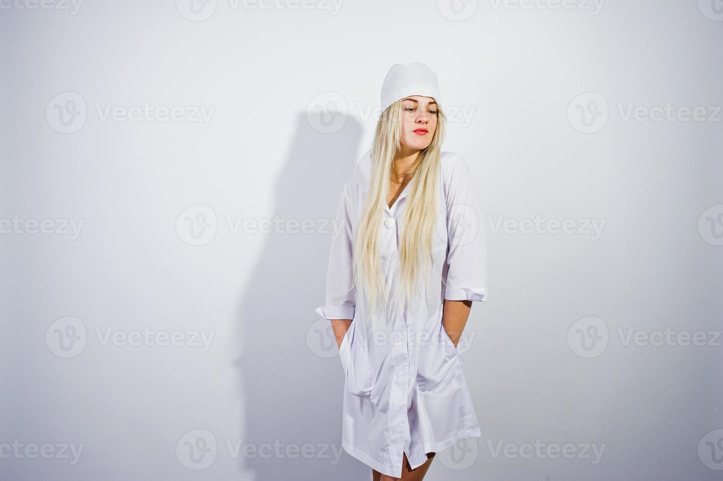 jolie blonde femme médecin ou infirmière en blouse de laboratoire isolée sur fond blanc. photo