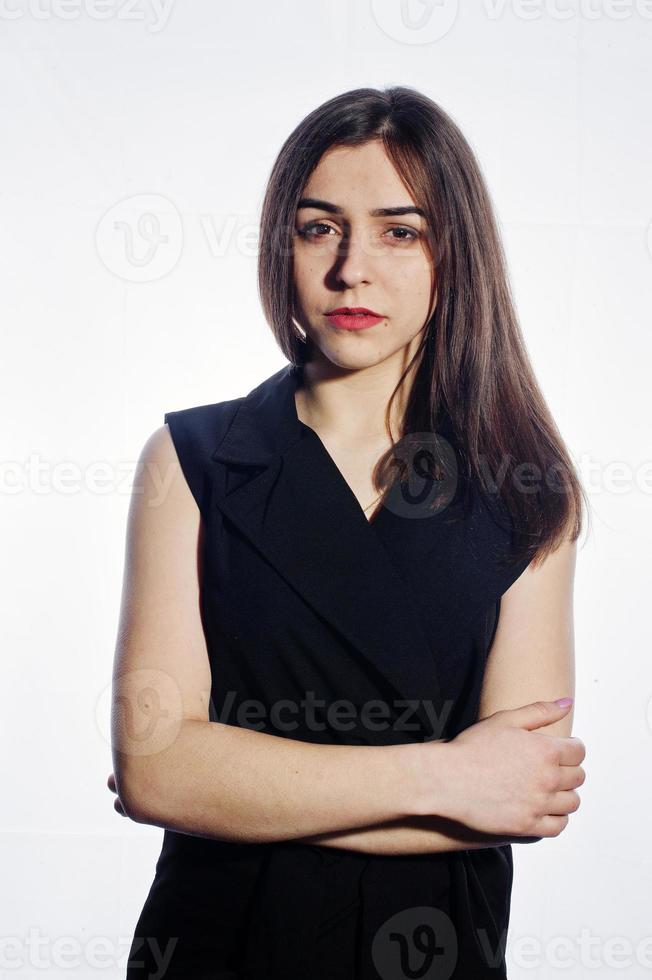 portrait émotionnel en gros plan d'une jeune fille brune en combinaison noire sur fond blanc. photo