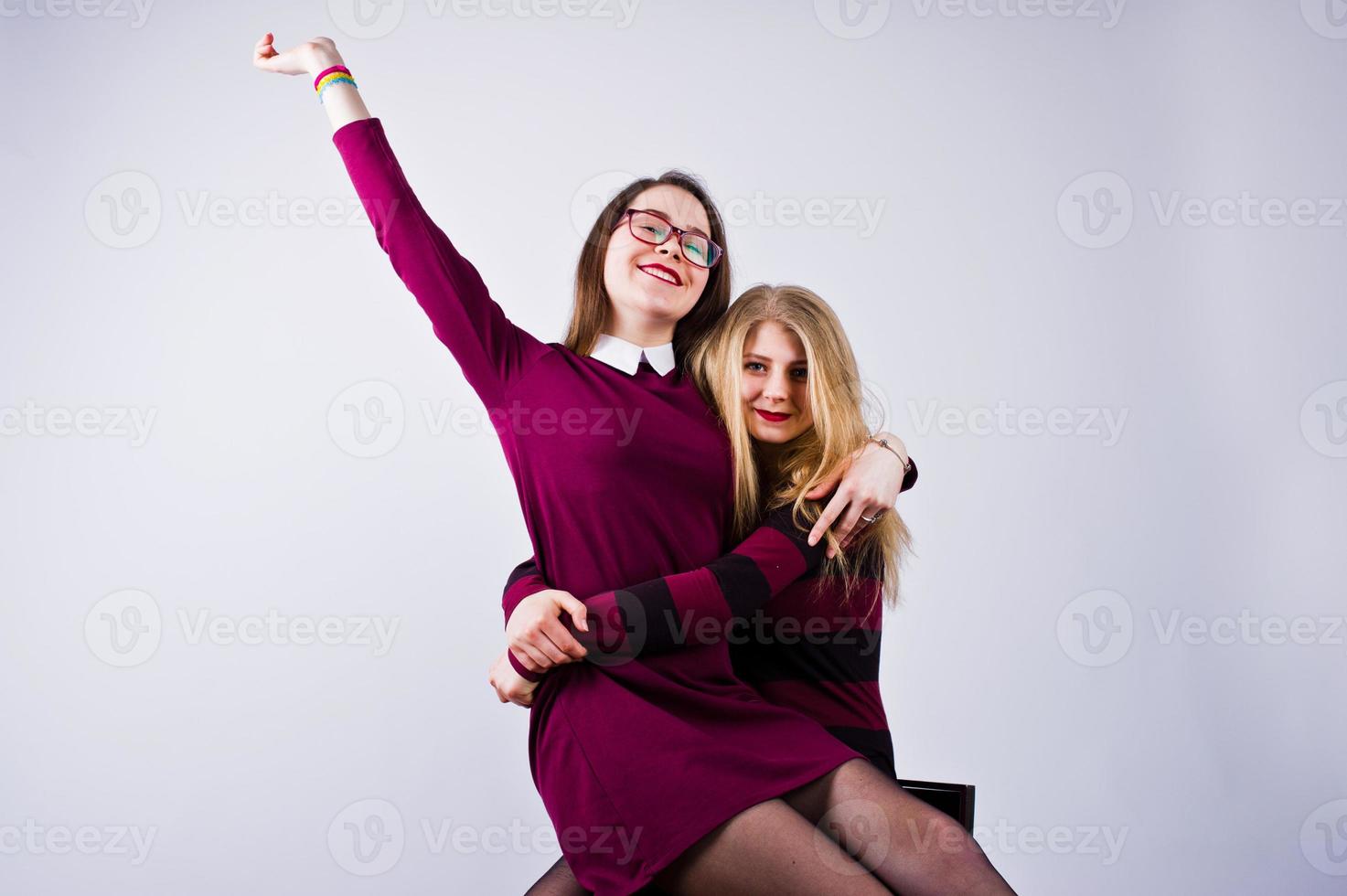 filles en robes violettes s'amusant et posant sur la chaise dans le studio. photo