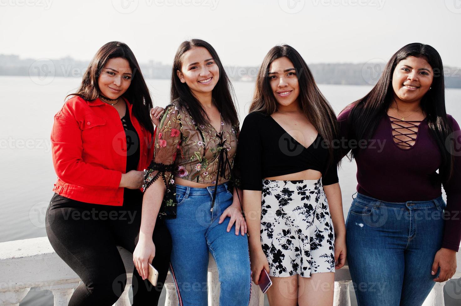 groupe de quatre filles latinos heureuses et jolies de l'équateur posées contre le bord du lac. photo