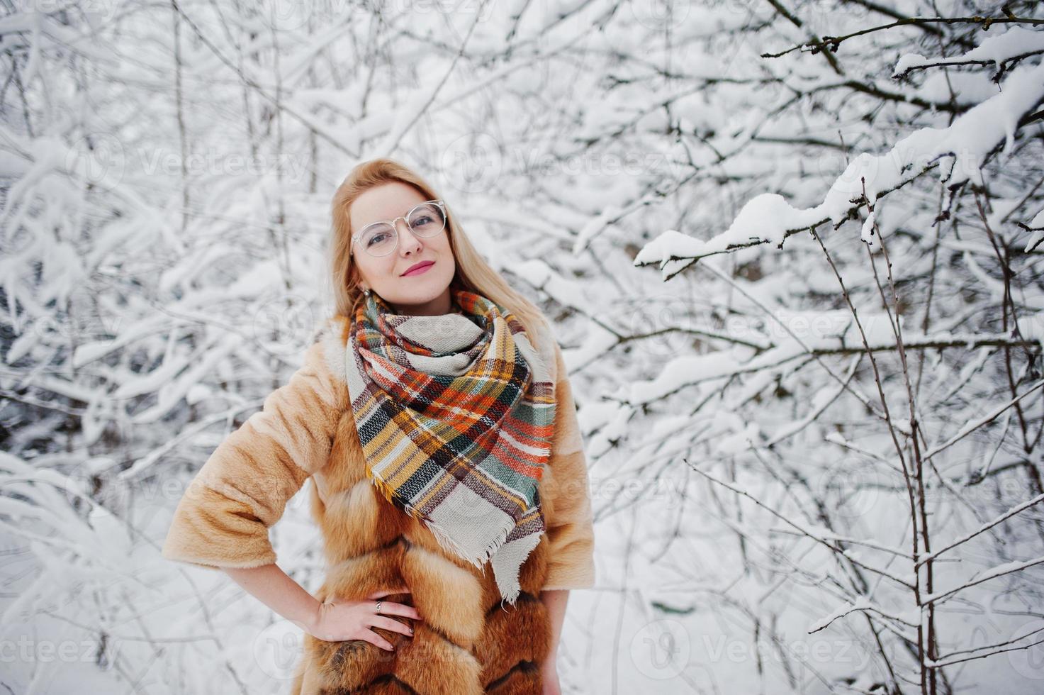 portrait d'une fille blonde à lunettes, manteau de fourrure rouge et écharpe le jour de l'hiver. photo