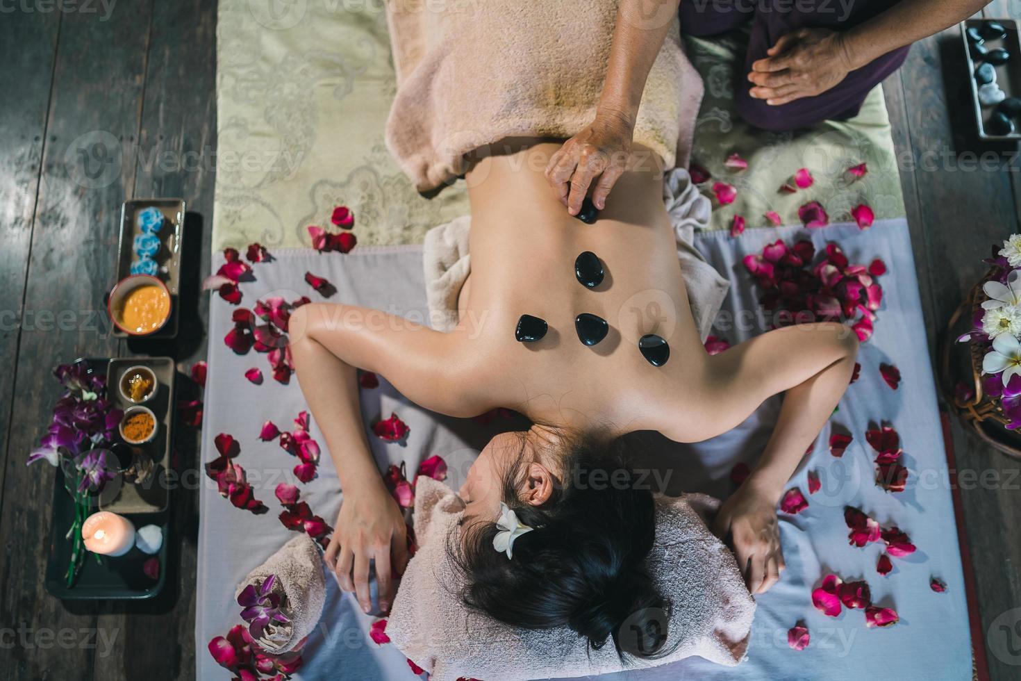 massage et spa traitement relaxant du syndrome de bureau en utilisant le style de massage thaï traditionnel aux pierres chaudes. asain femme masseuse faisant des massages traite les maux de dos, les douleurs au bras, le stress pour les femmes fatiguées du travail. photo