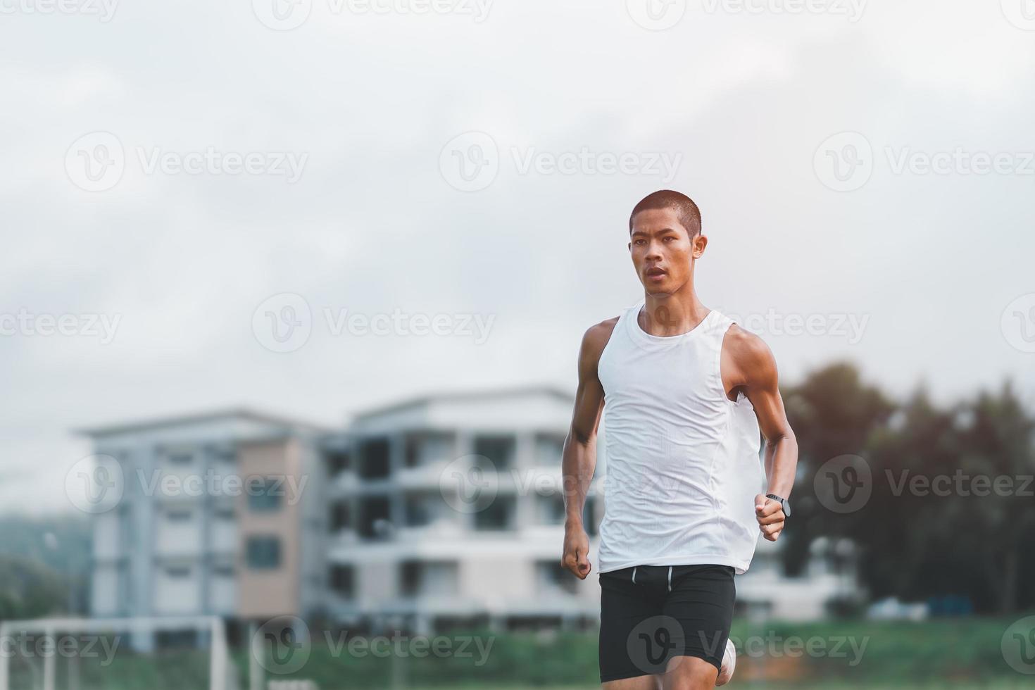 l'athlète sportif coureur s'entraîne sur la voie du stade le matin. coureur homme portant un gilet blanc pour s'entraîner à courir se préparer à la course de compétition. notion sportive. photo