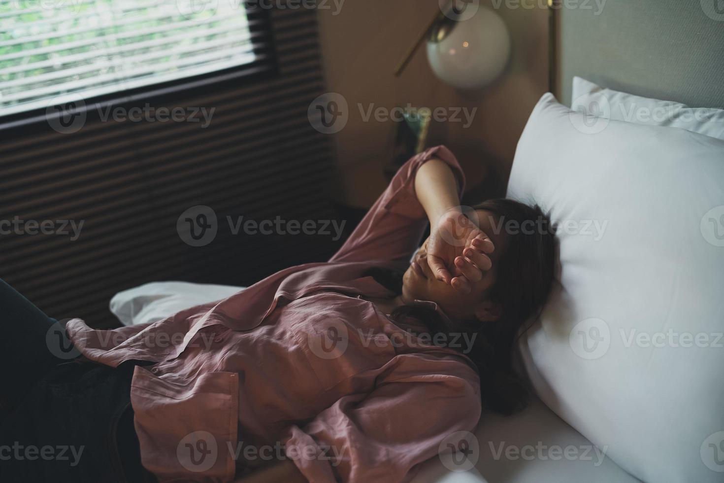 femme asiatique triste souffrant d'insomnie dépressive éveillée et assise seule sur le lit dans la chambre. harcèlement sexuel et violence à l'égard des femmes, concept de santé photo