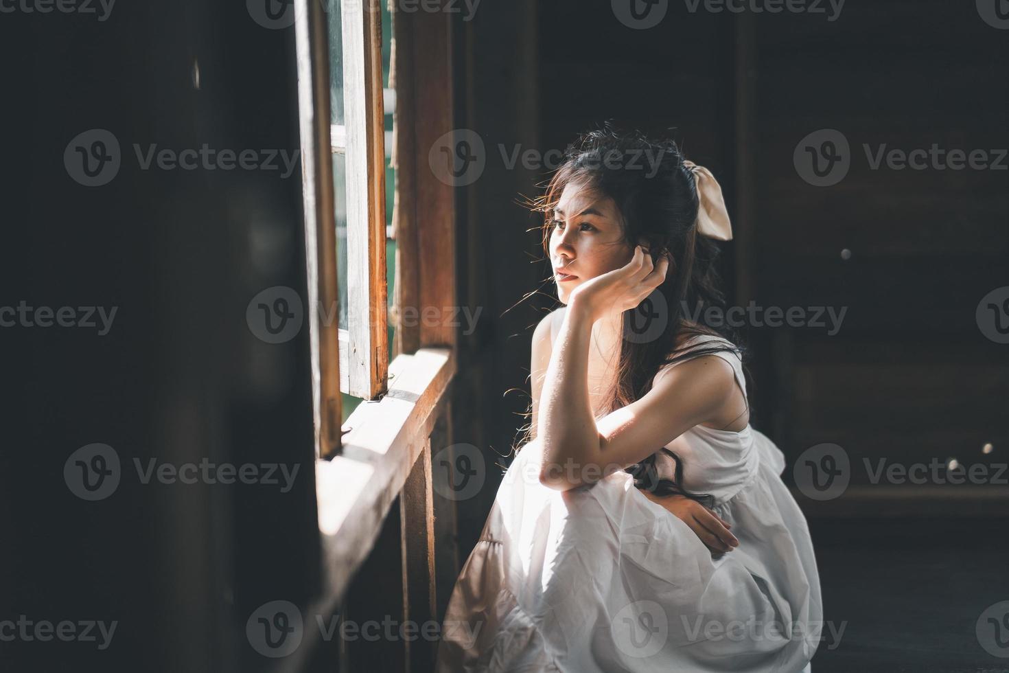 triste femme asiatique portant une robe blanche souffrant de dépression insomnie éveillée et assise seule sur le lit dans une chambre vintage. le harcèlement sexuel et la violence contre les femmes. photo