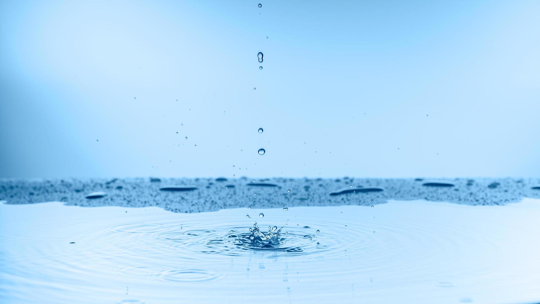 tonalité de couleur bleue de la goutte d'eau de pluie en gros plan tombant sur le sol photo