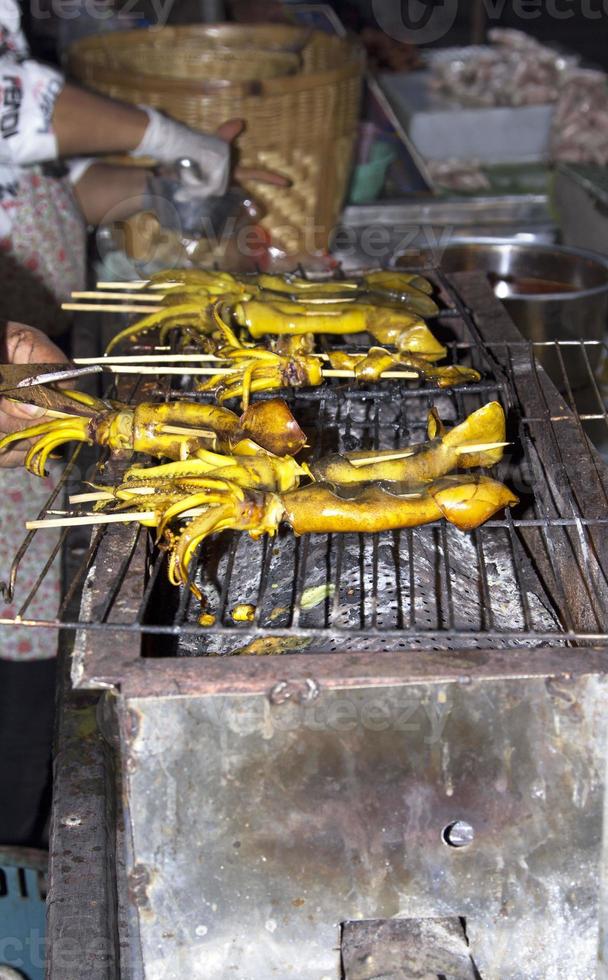 calmars grillés sur un gril à charbon de bois, un gril chaud pour que les clients mangent de délicieux calmars vendus dans les rues que l'on peut voir en Thaïlande la nuit et à chaque festival thaïlandais. photo
