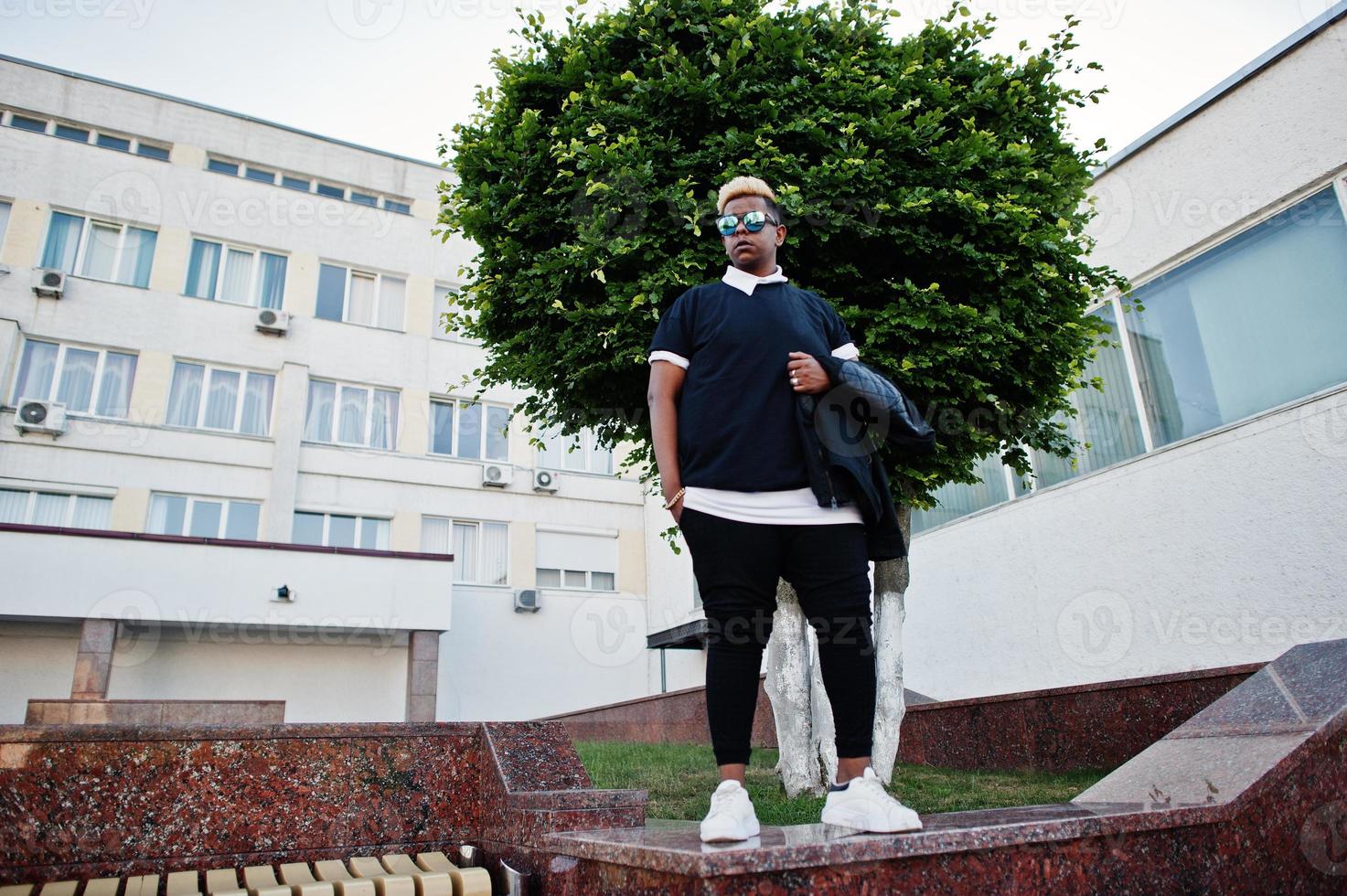 garçon musulman arabe élégant avec à l'origine des cheveux et des lunettes de soleil posés dans les rues photo