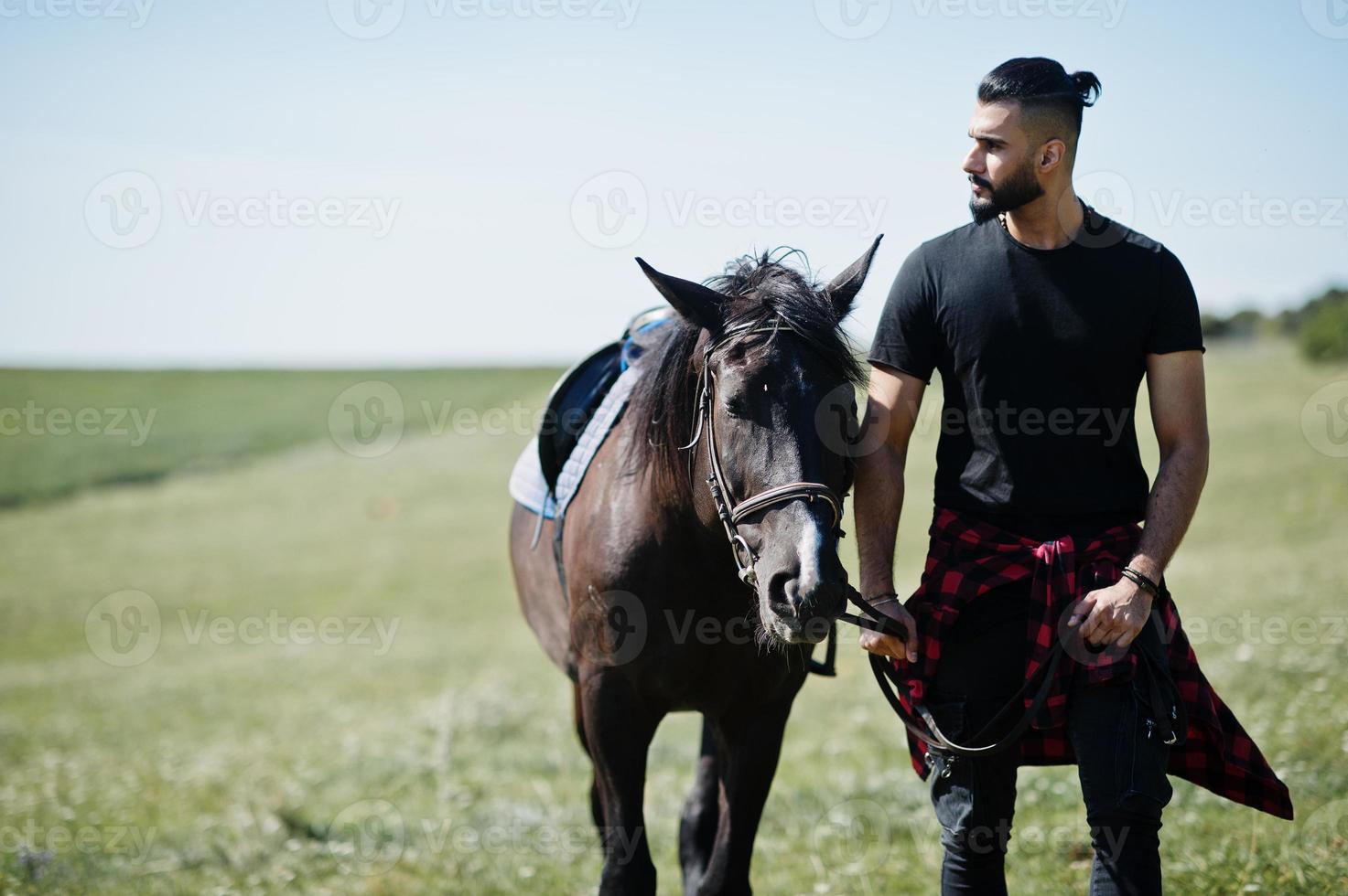 homme arabe à barbe haute en noir avec cheval arabe. photo