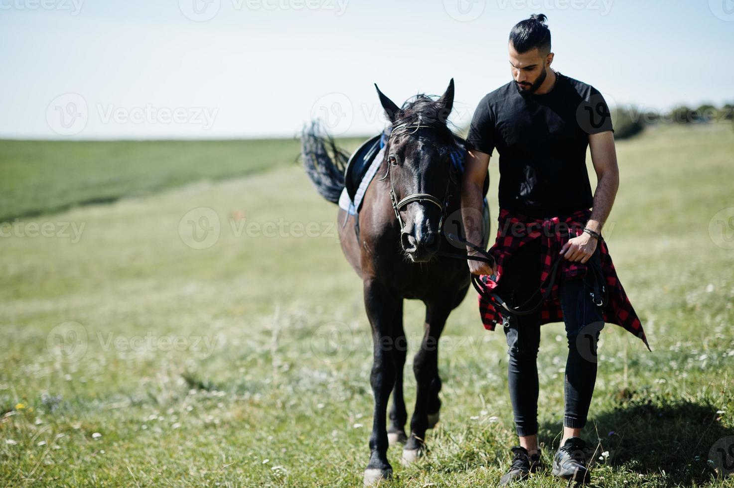 homme arabe à barbe haute en noir avec cheval arabe. photo