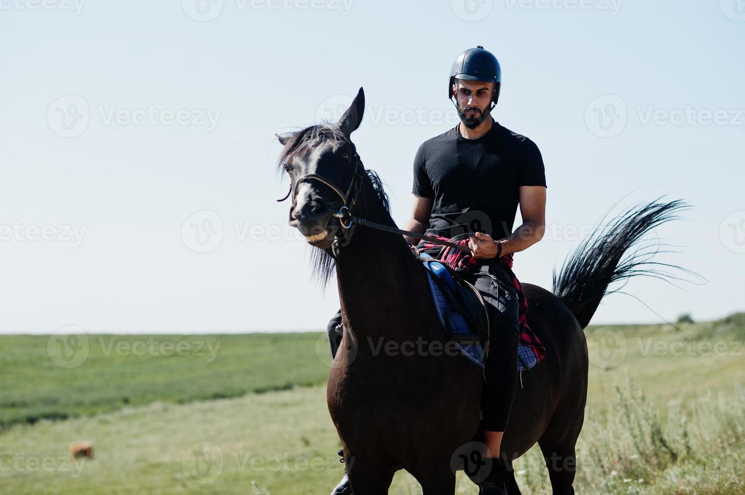 homme arabe à grande barbe portant un casque noir, monter à cheval arabe. photo