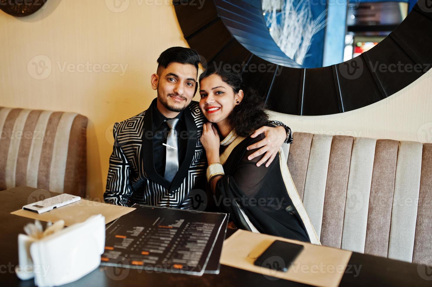 charmant couple indien amoureux, porter au sari et costume élégant, posé sur le restaurant. photo