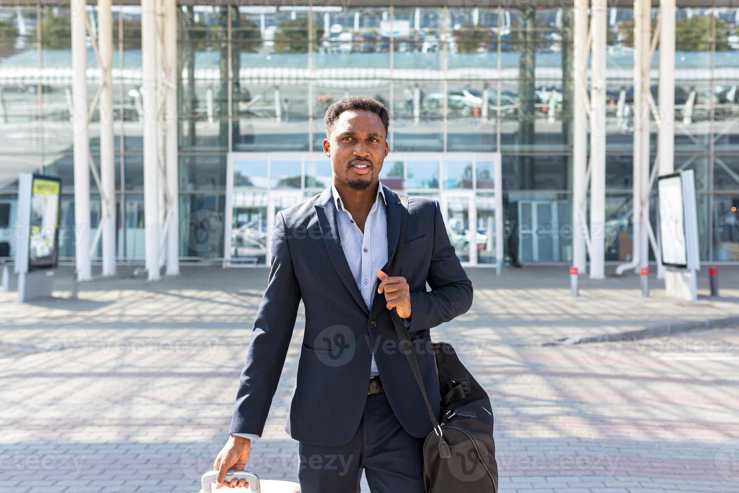 un homme d'affaires touristique afro-américain marche dans un bâtiment de transport public avec un arrière-plan de bagages photo