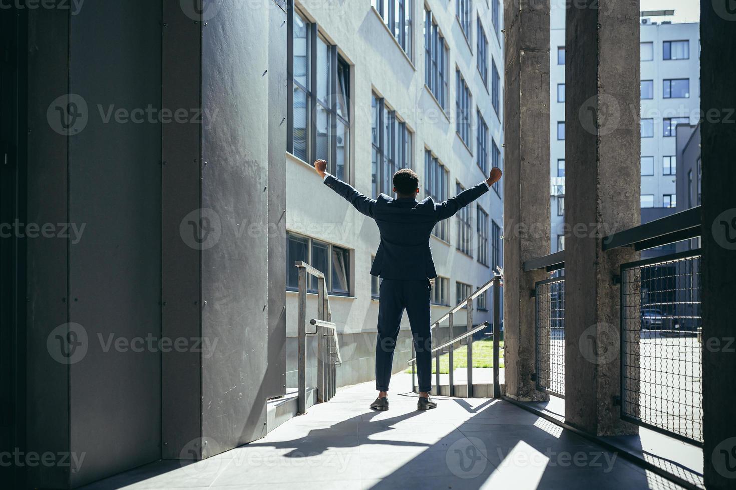 homme d'affaires afro-américain prospère avec les bras en l'air célébrant la victoire. photo