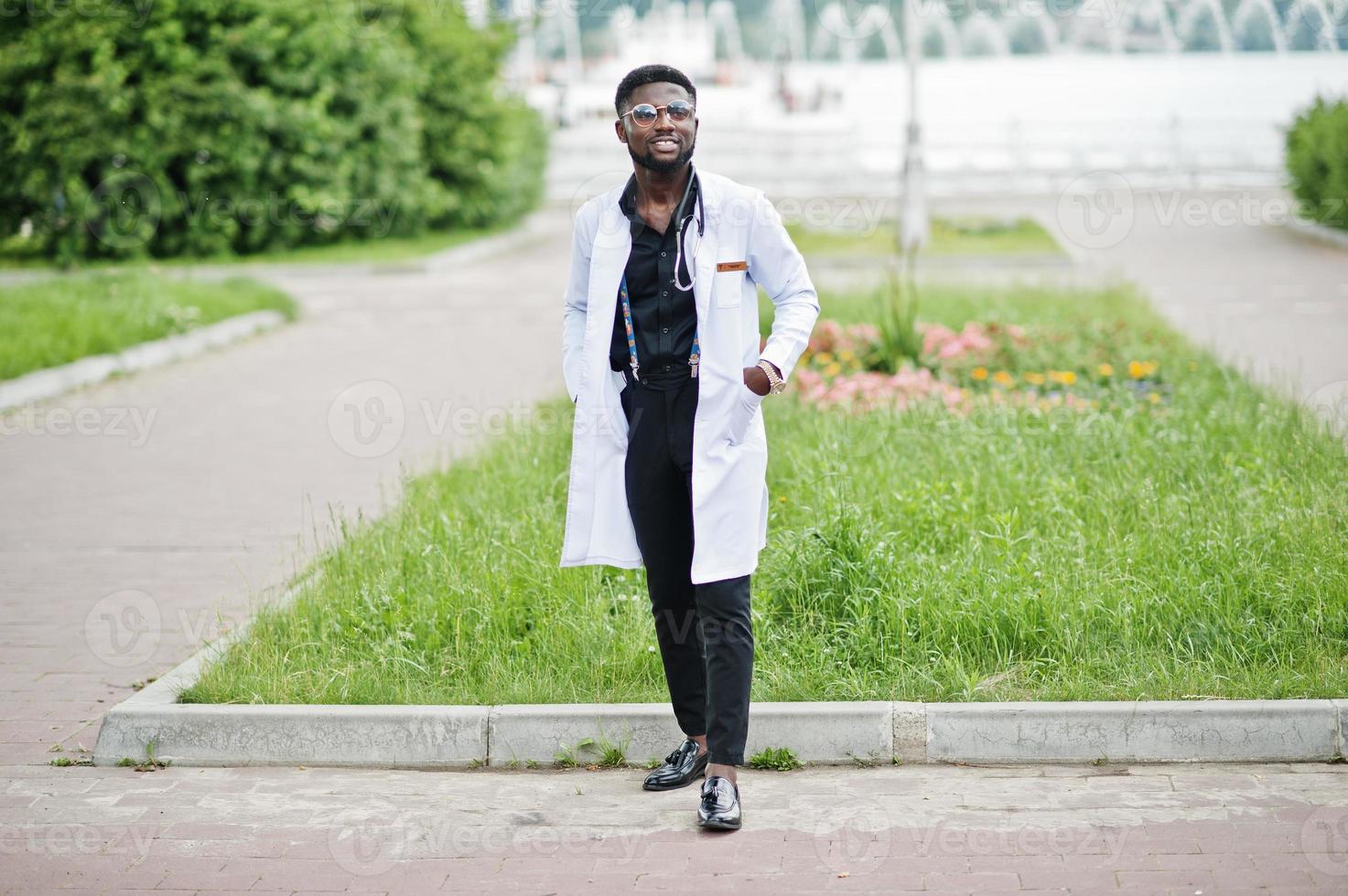 jeune médecin de sexe masculin afro-américain en blouse blanche avec un stéthoscope posé à l'extérieur. photo