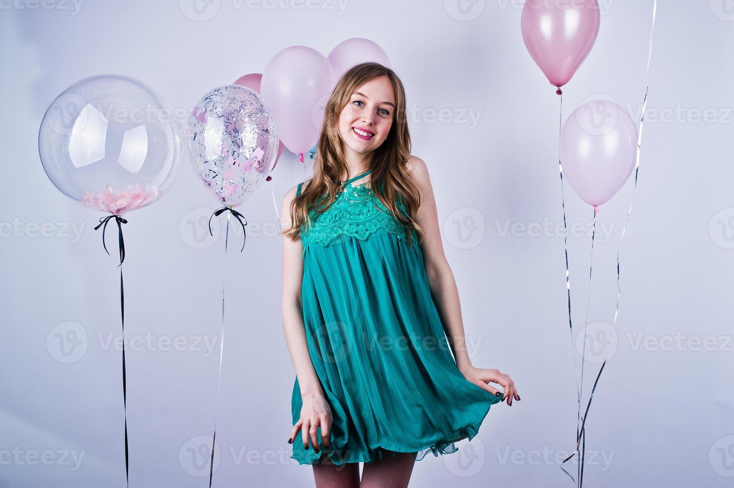 fille heureuse en robe turquoise verte avec des ballons colorés isolés sur blanc. célébrer le thème de l'anniversaire. photo