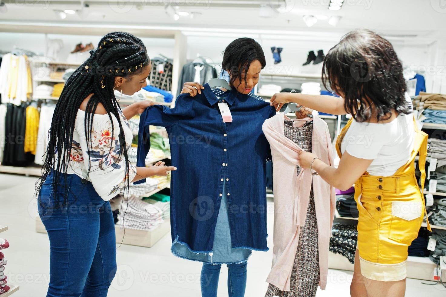 trois femmes africaines choisissant des vêtements au magasin. Jour de shopping. photo