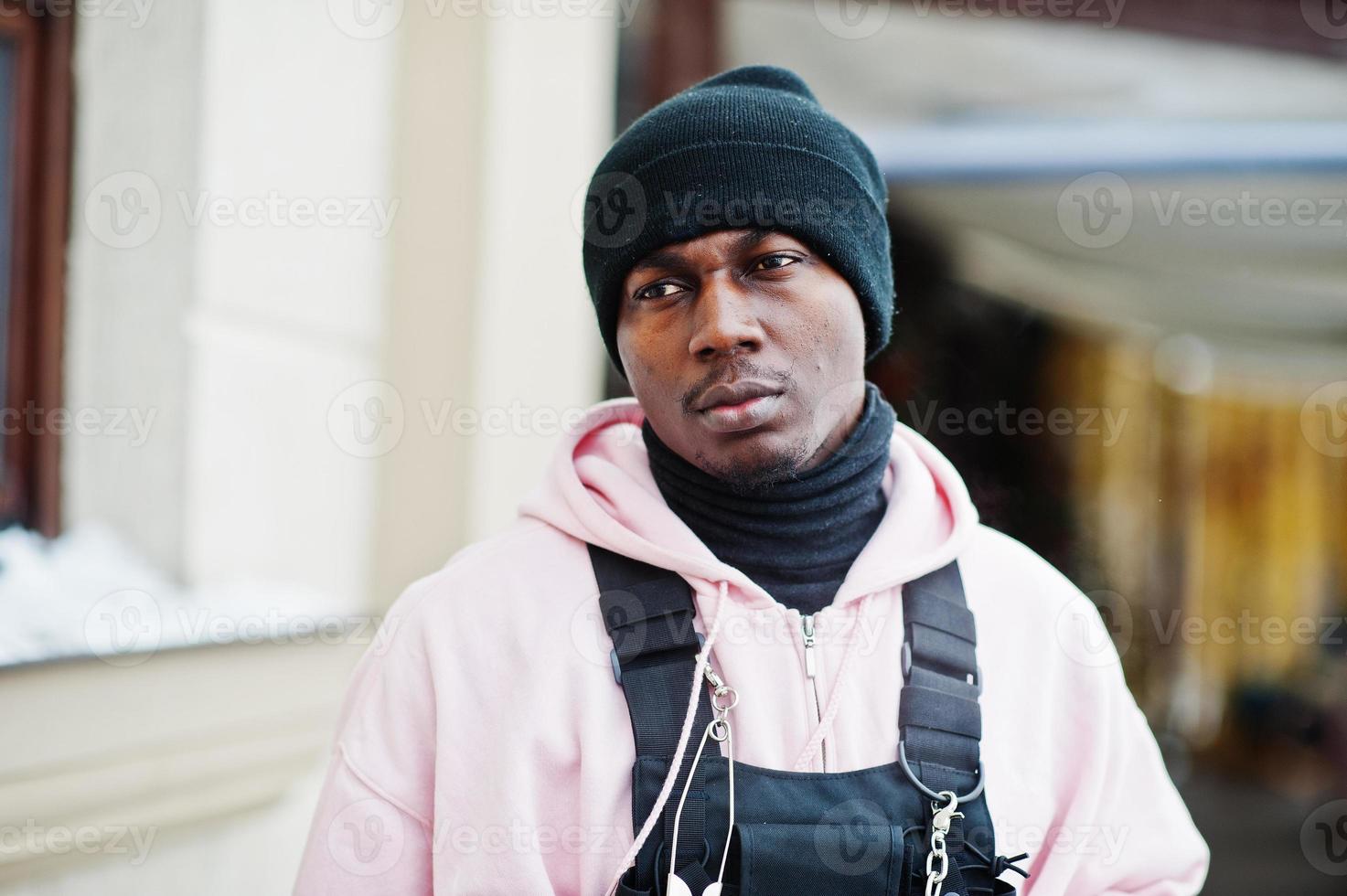 tête en gros plan d'un homme afro-américain élégant de style urbain en sweat à capuche rose et chapeau noir posé. photo