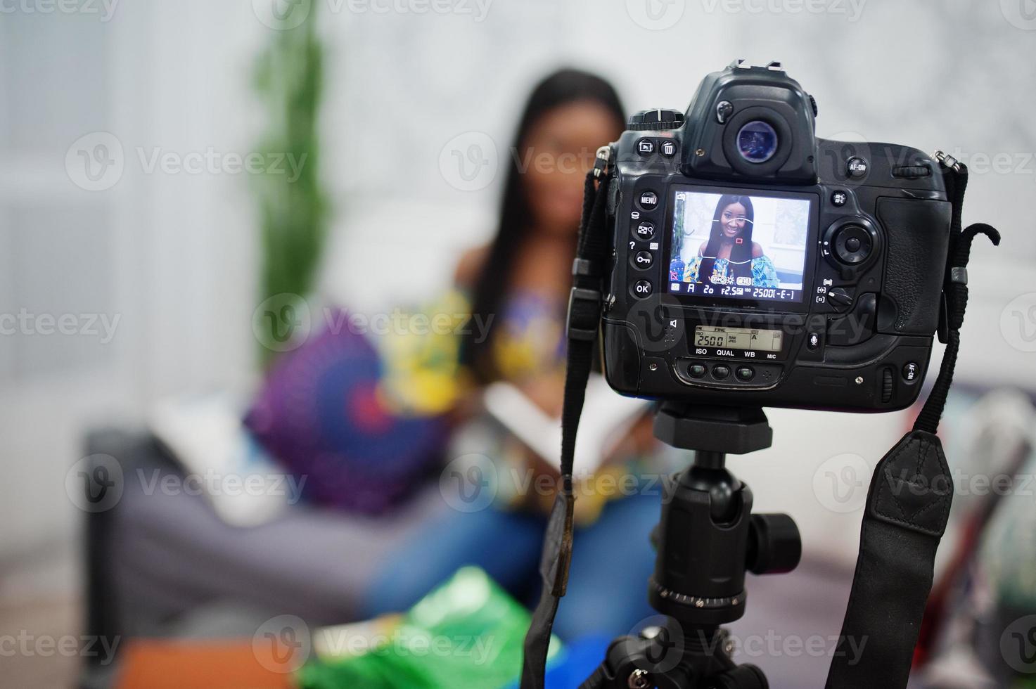 jolie femme afro-américaine réalisant une vidéo pour son blog à l'aide d'un appareil photo numérique monté sur trépied. jeune blogueuse ou vlogger à la caméra.