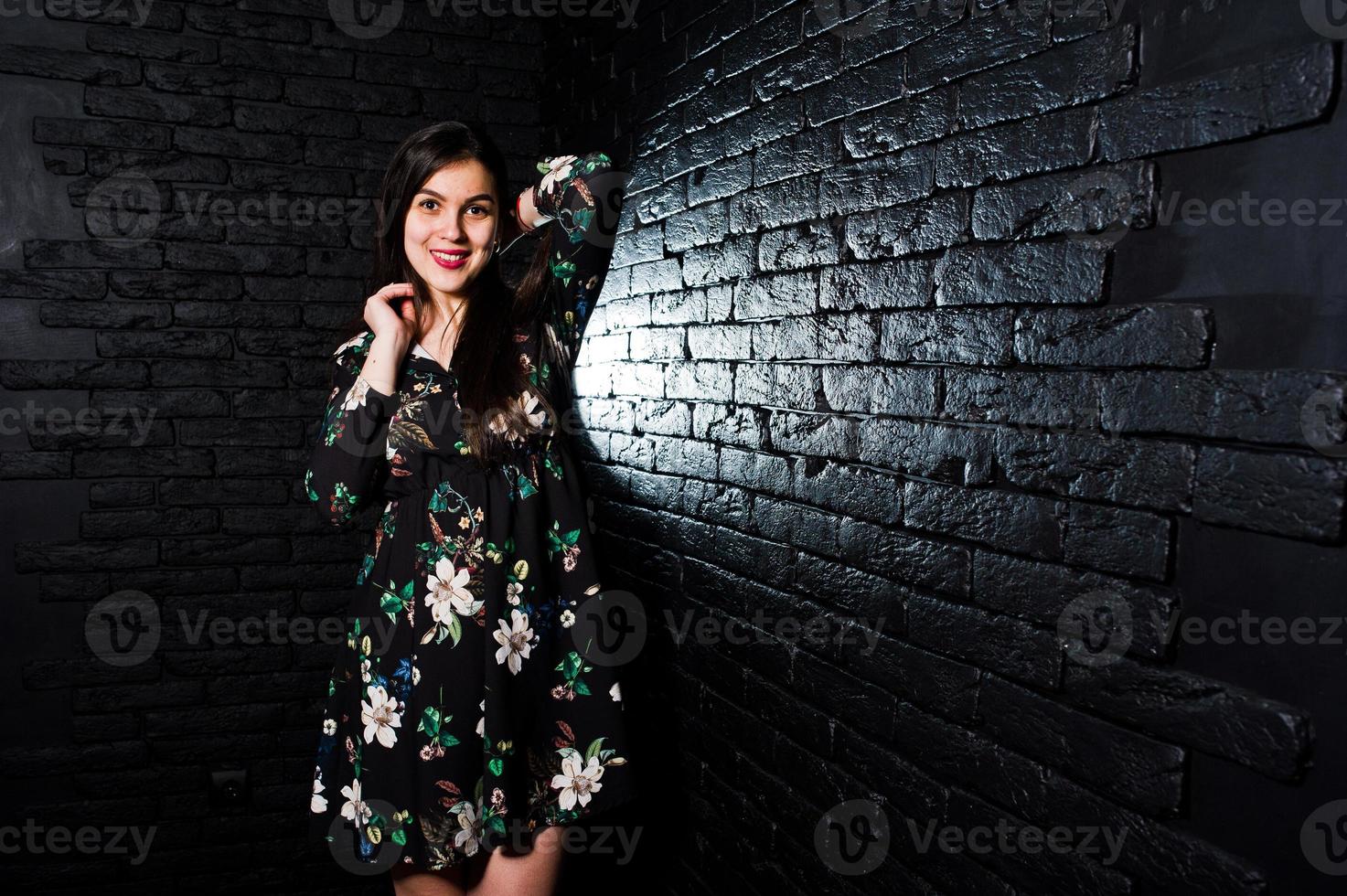 portrait d'une fabuleuse jeune femme en robe à fleurs dans le studio sombre. photo