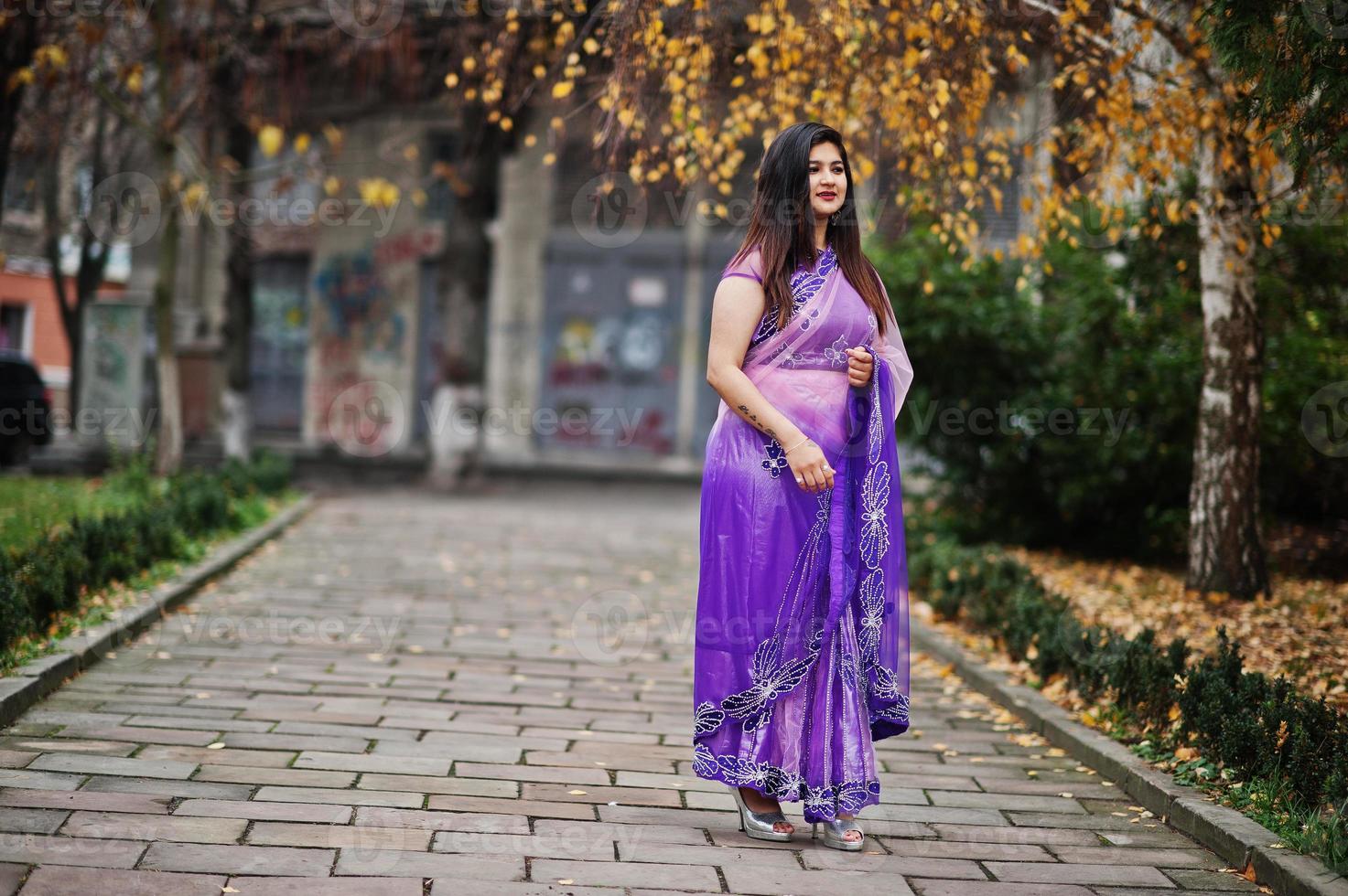 fille hindoue indienne au sari violet traditionnel posé dans la rue d'automne. photo