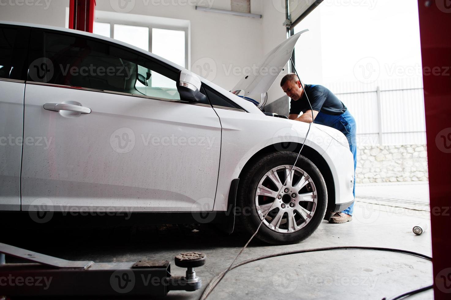 thème de la réparation et de l'entretien des voitures. mécanicien en uniforme travaillant dans le service automobile. photo