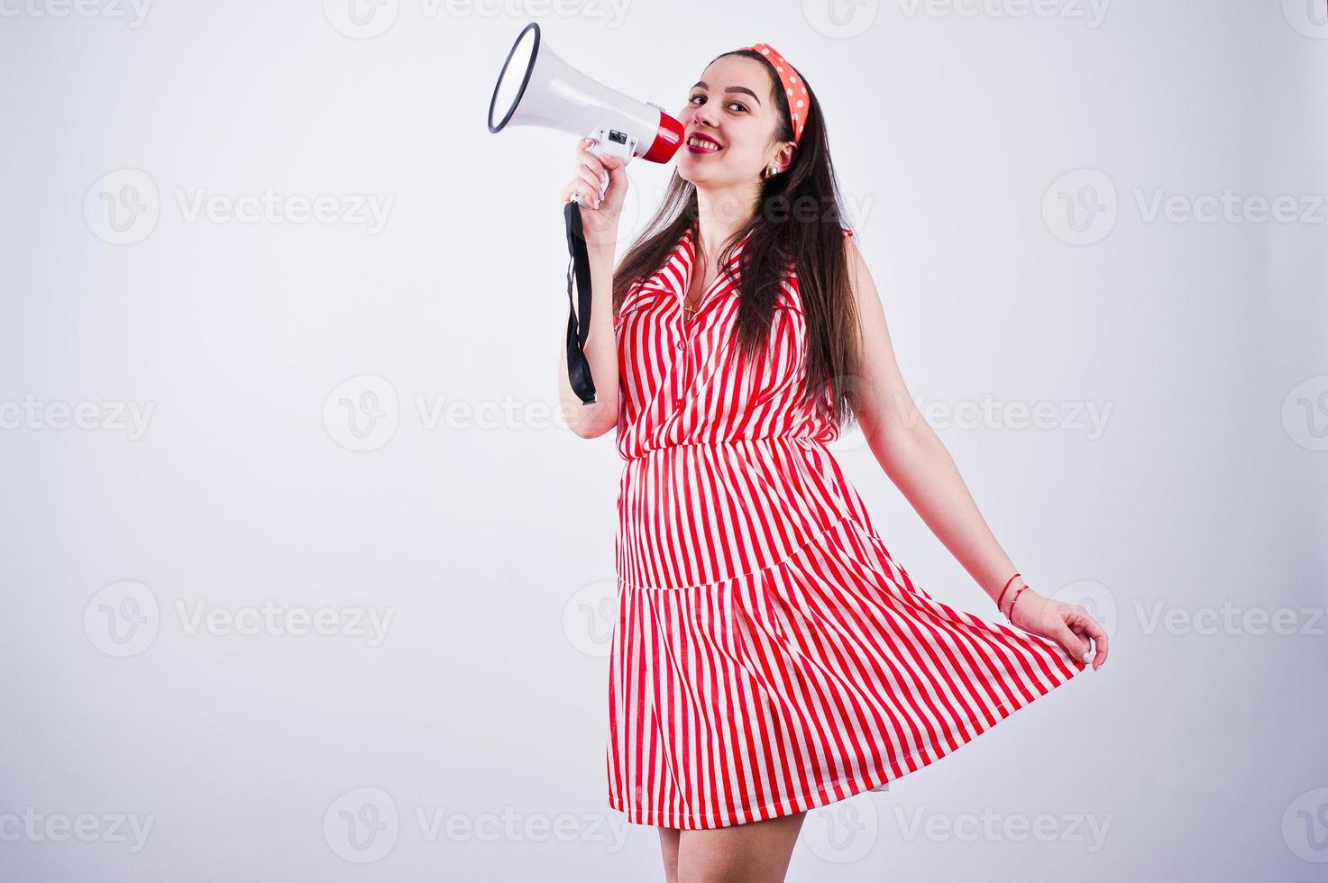 portrait d'une belle jeune femme en robe rouge parlant dans un mégaphone. photo