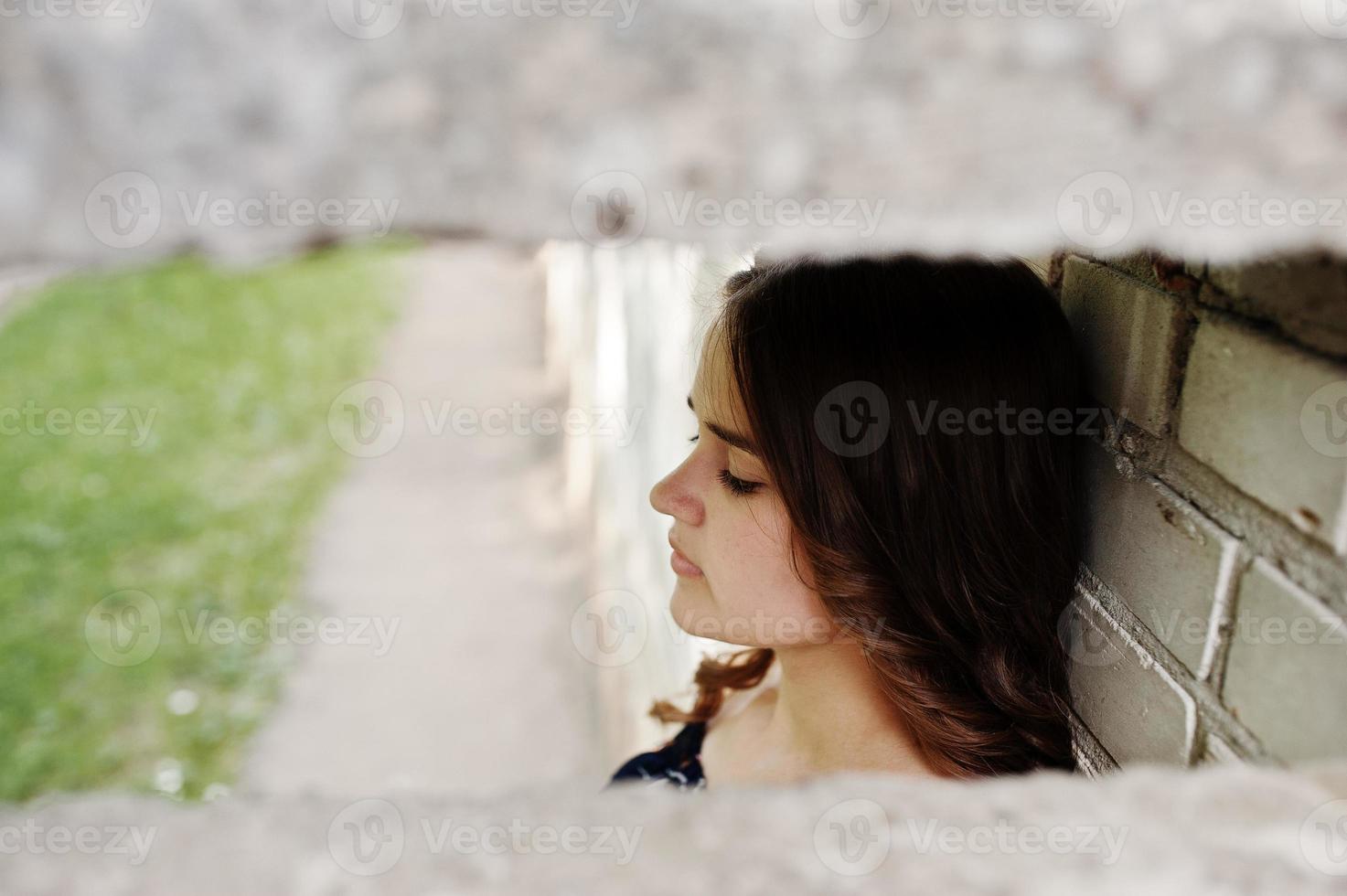 portrait en gros plan d'un visage féminin à côté du mur de briques. photo