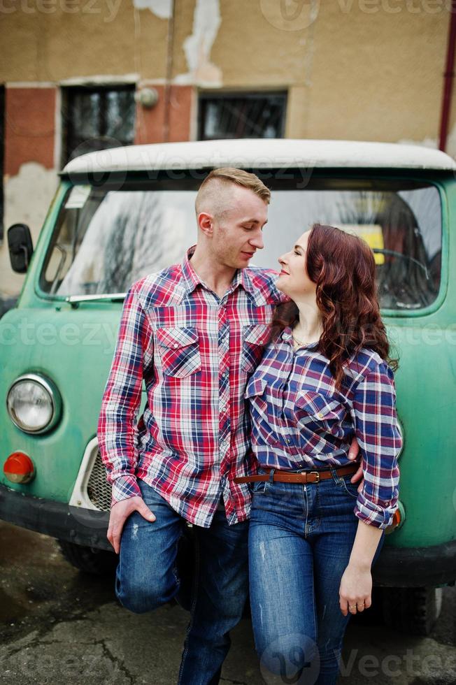 couple élégant portant une chemise à carreaux amoureux ensemble contre une vieille fourgonnette. photo