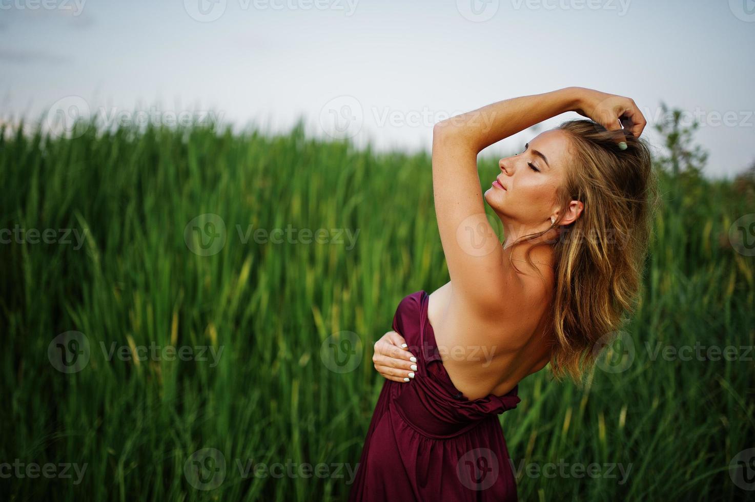 femme sensuelle blonde en robe marsala rouge posant dans les roseaux. photo