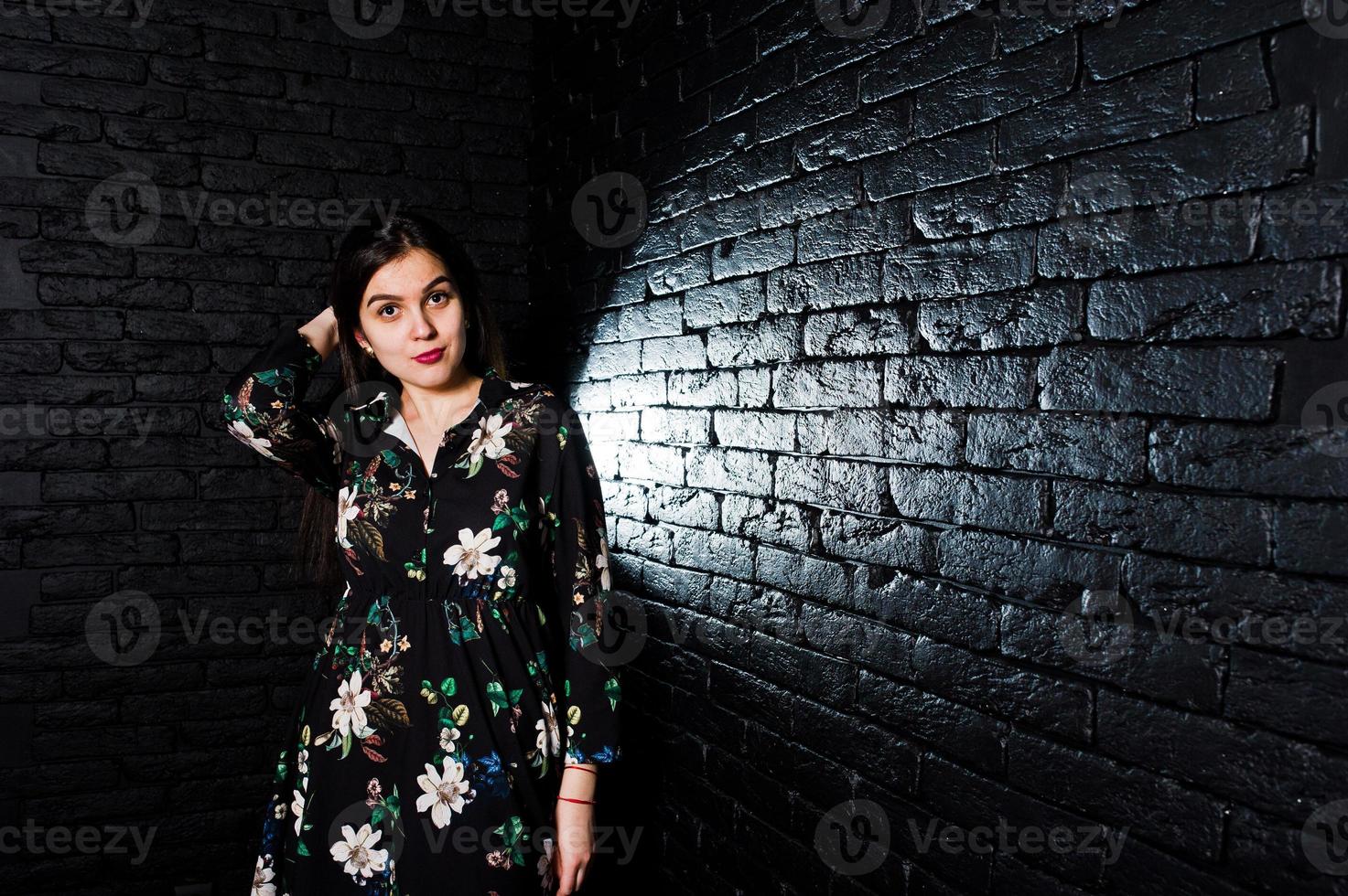 portrait d'une fabuleuse jeune femme en robe à fleurs dans le studio sombre. photo