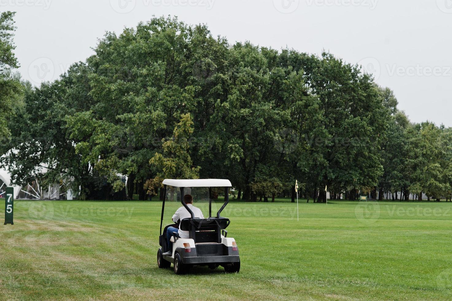 homme conduisant une voiture de golf sur le terrain de golf. photo