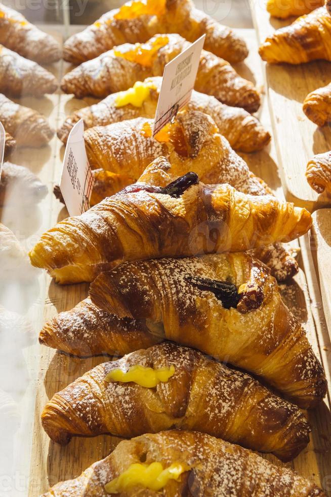 diverses saveurs de croissant ou comme en italie leur brioche appelée exposée dans une boulangerie à milan, italie avec un prix et un signe - albicocca signifie confiture en italien photo