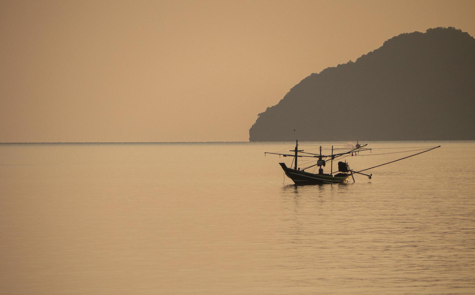 un petit bateau de pêche amarré au milieu de la mer au coucher du soleil. photo