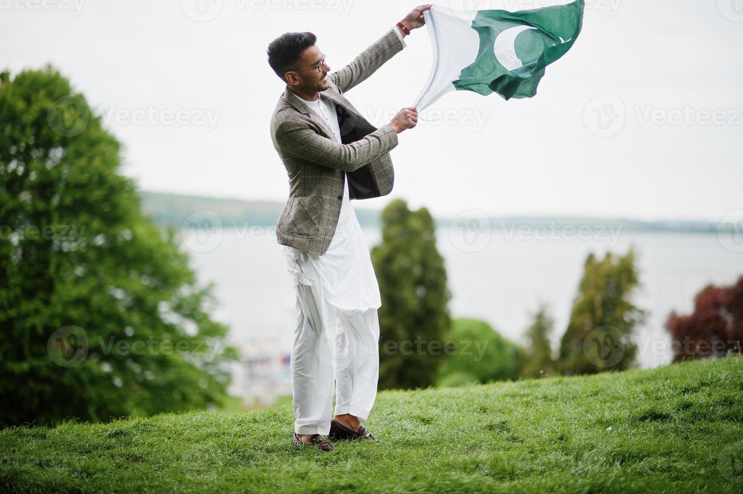 l'homme pakistanais élégant porte des lunettes et une veste tient le drapeau du pakistan. photo