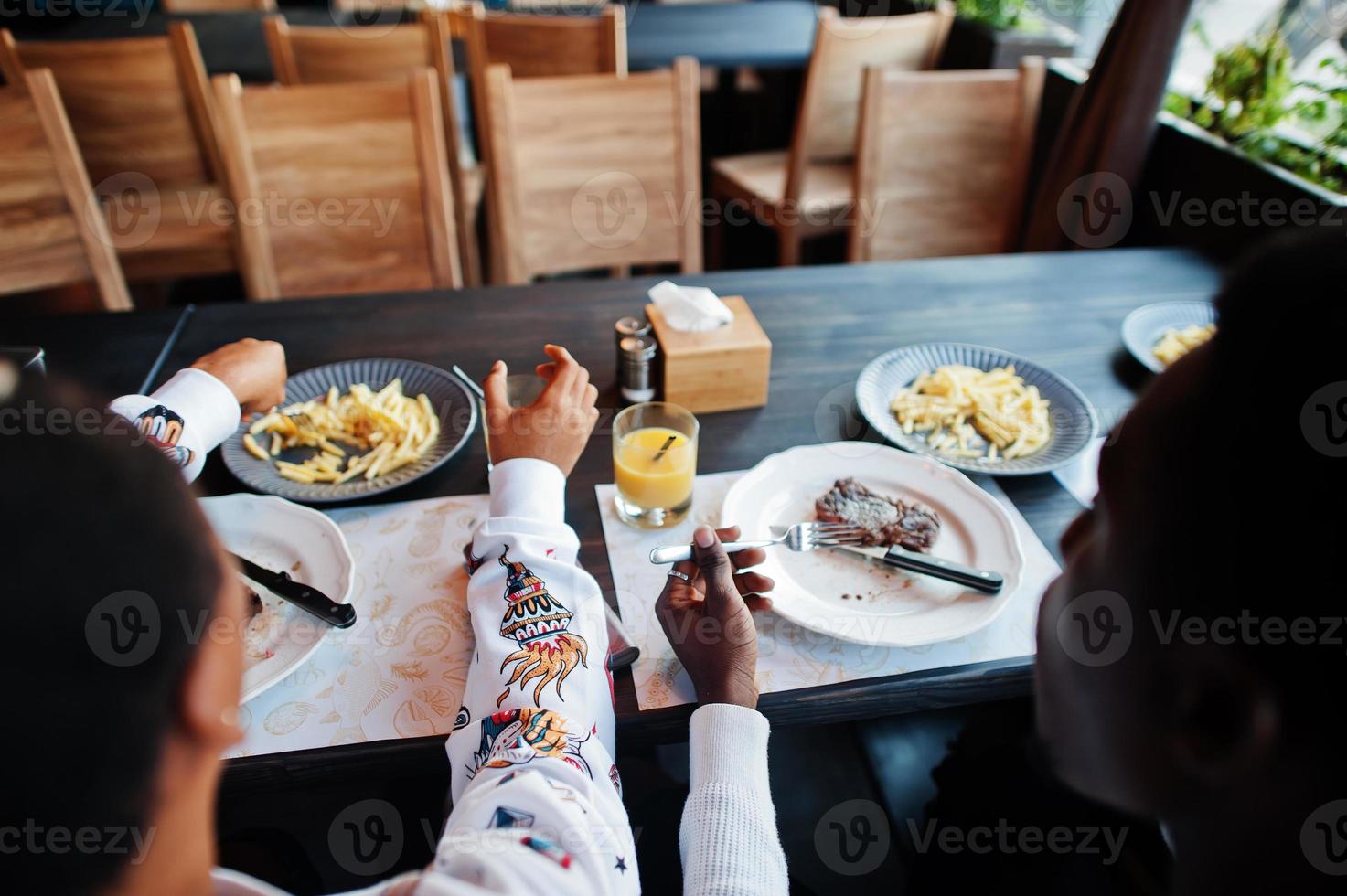 amis africains heureux assis, bavardant au café et mangeant de la nourriture. groupe de peuples noirs se réunissant au restaurant et dînant. photo