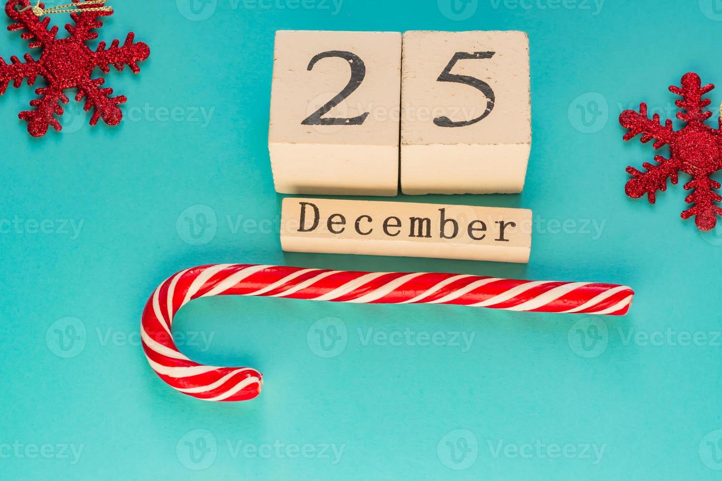 calendrier en bloc de bois indiquant le 25 décembre. vacances de Noël. carte de voeux avec des cannes de bonbon et des flocons de neige étincelants. photo