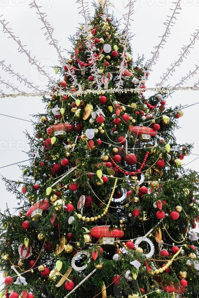 gros plan sur un sapin de noël décoré de boules, de jouets et de guirlandes. agencement de rue festif photo