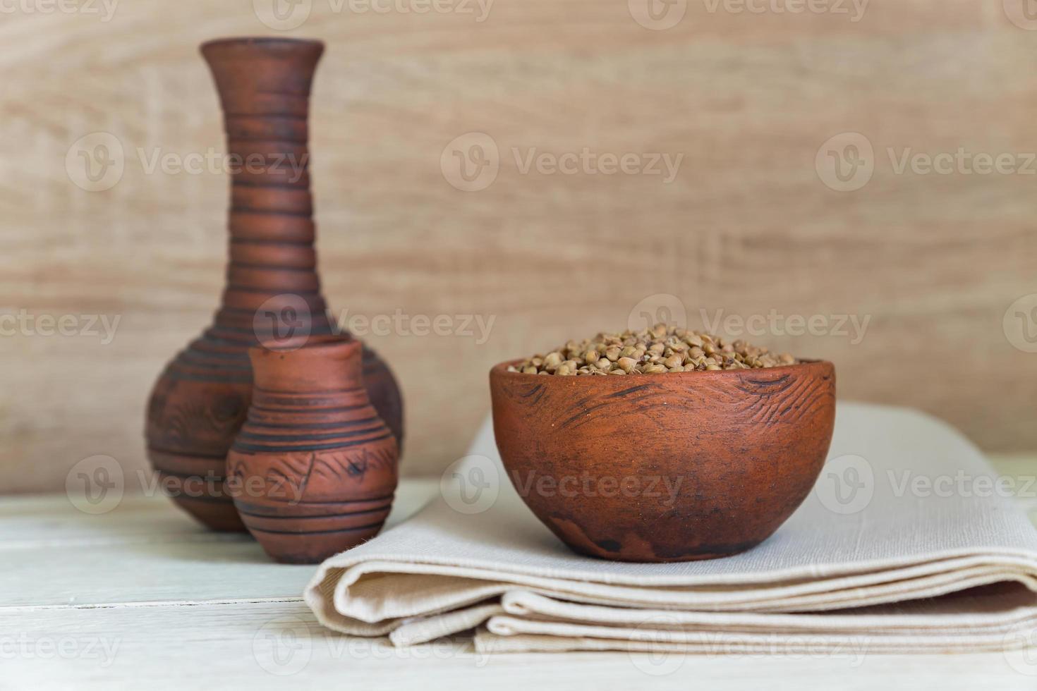 sarrasin sec dans un bol d'argile brune sur une table en bois. céréales sans gluten pour une alimentation saine photo