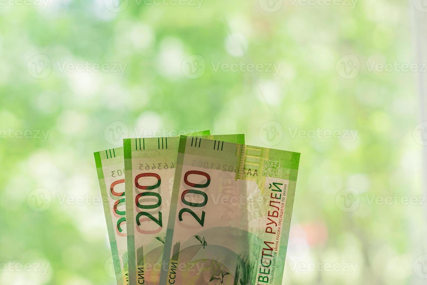 nouveaux billets de banque russes sur fond vert bokeh. deux cents roubles. papier-monnaie en espèces. photo