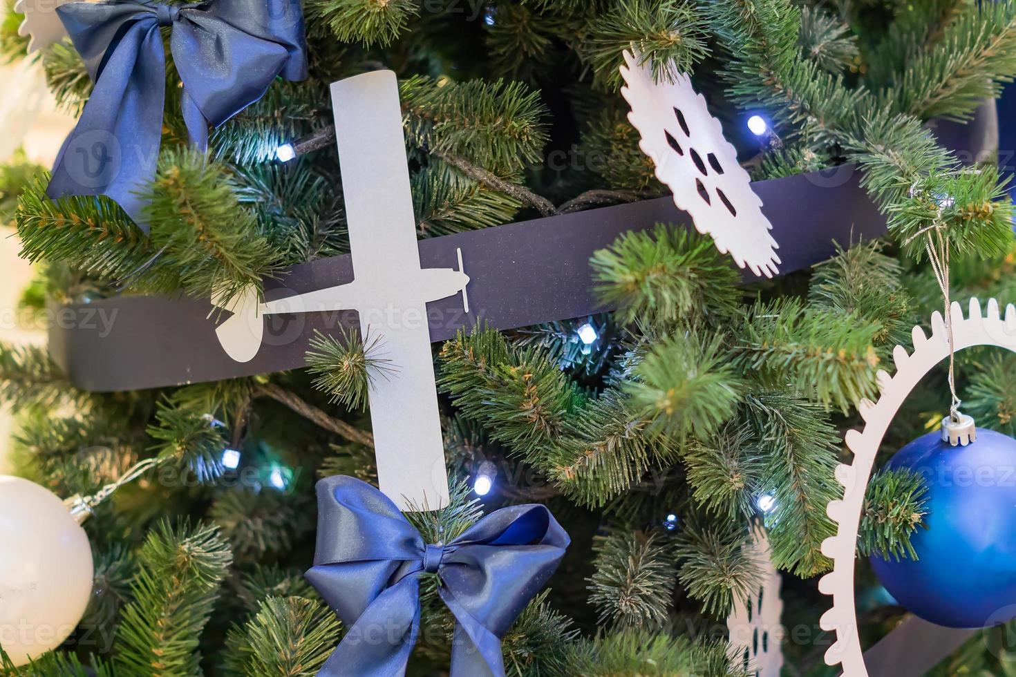 gros plan sur un sapin de noël décoré d'un avion blanc et de boules bleues fond de nouvel an photo