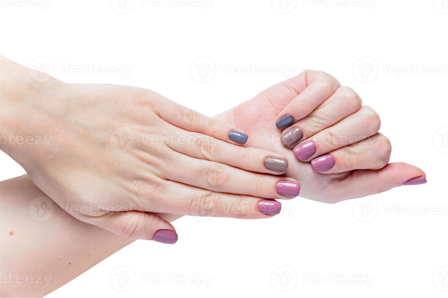 mains de la belle jeune femme isolées sur fond blanc. manucure féminine tendance et élégante avec vernis à ongles gris, rose et marron. photo