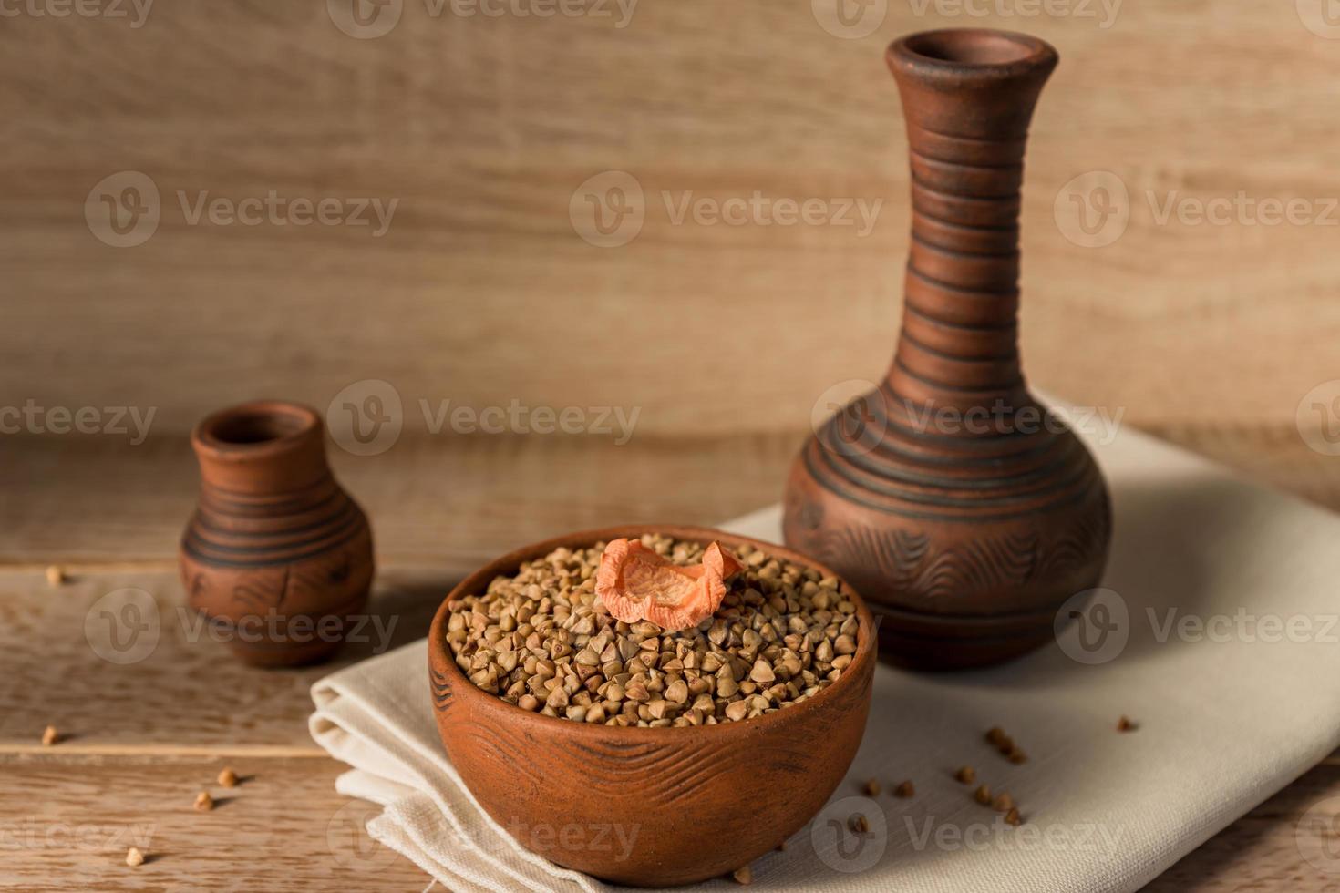 sarrasin sec dans un bol d'argile brune sur une table en bois. céréales sans gluten pour une alimentation saine photo