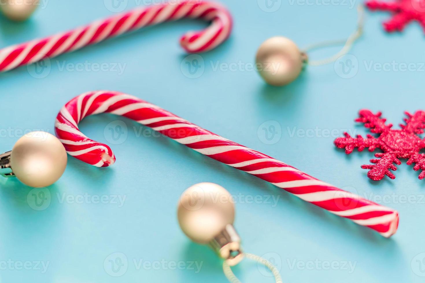 carte de voeux joyeux noël et bonne année. deux cannes de bonbon, des boules d'or et des flocons de neige étincelants sur fond bleu. photo