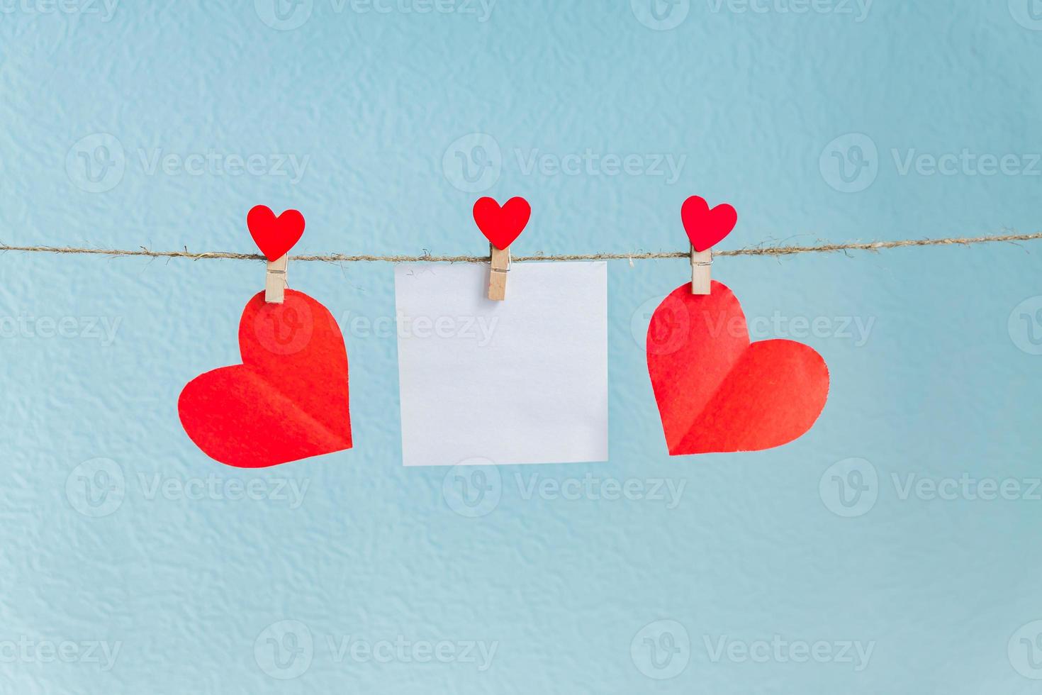 cartes vierges sur des épingles avec des coeurs rouges. maquette pour le texte et fond bleu pour les salutations de la saint valentin photo