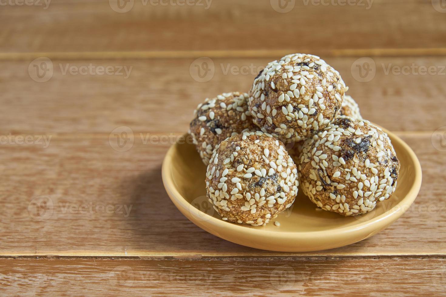 boulettes de protéines de sésame à l'avoine. bouchées énergétiques faibles en gras avec flocons d'avoine, noix de sésame et pruneaux sur fond de bois photo