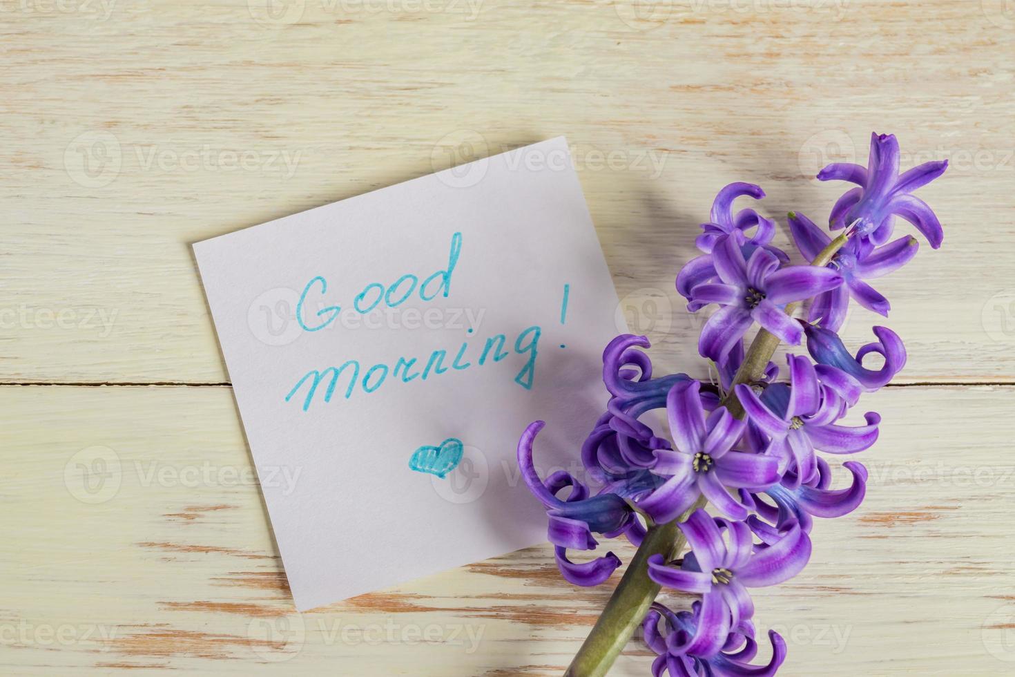 Bonjour étiquette en papier et fleur de jacinthe violette sur table en bois photo